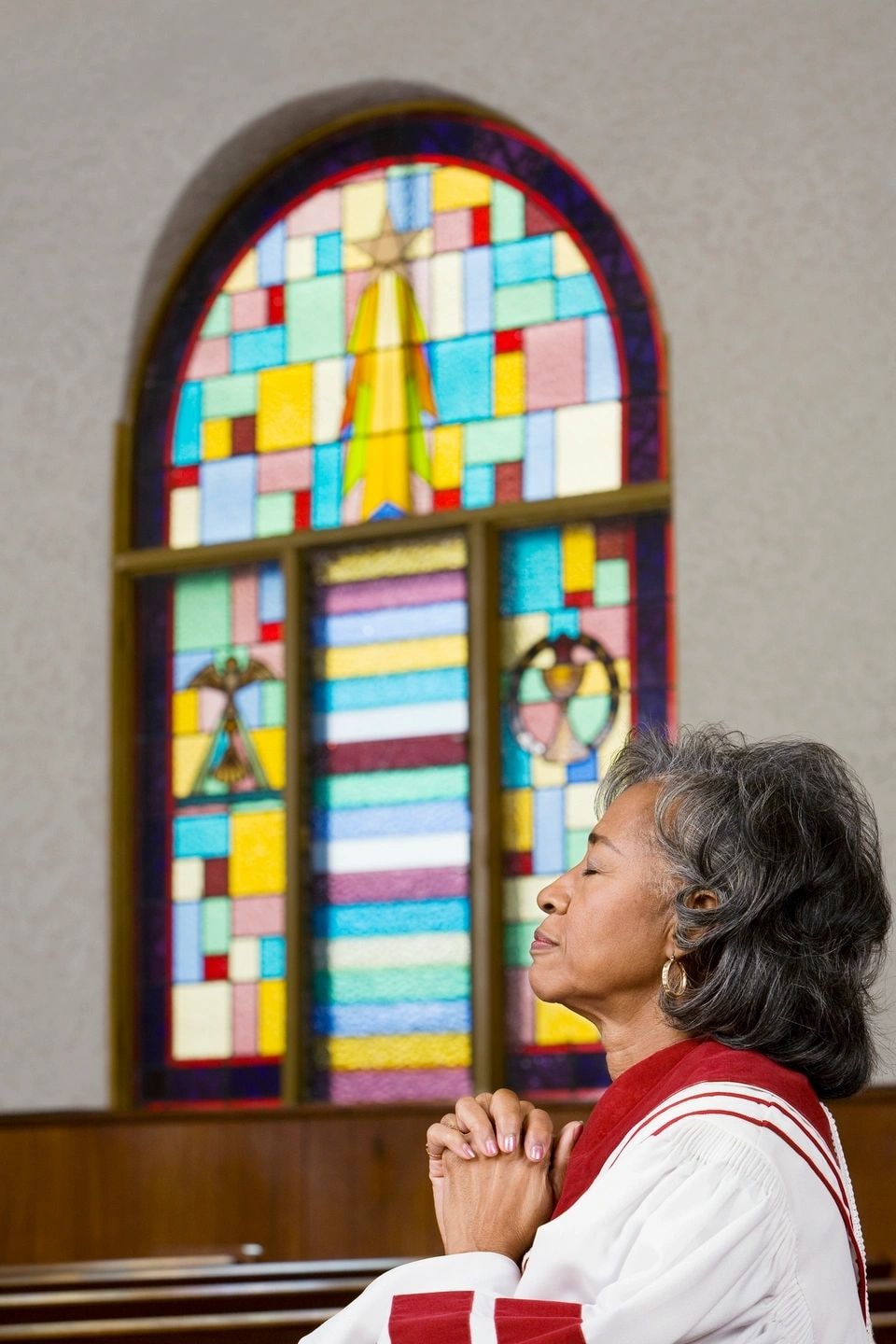 Woman praying before stained glass window