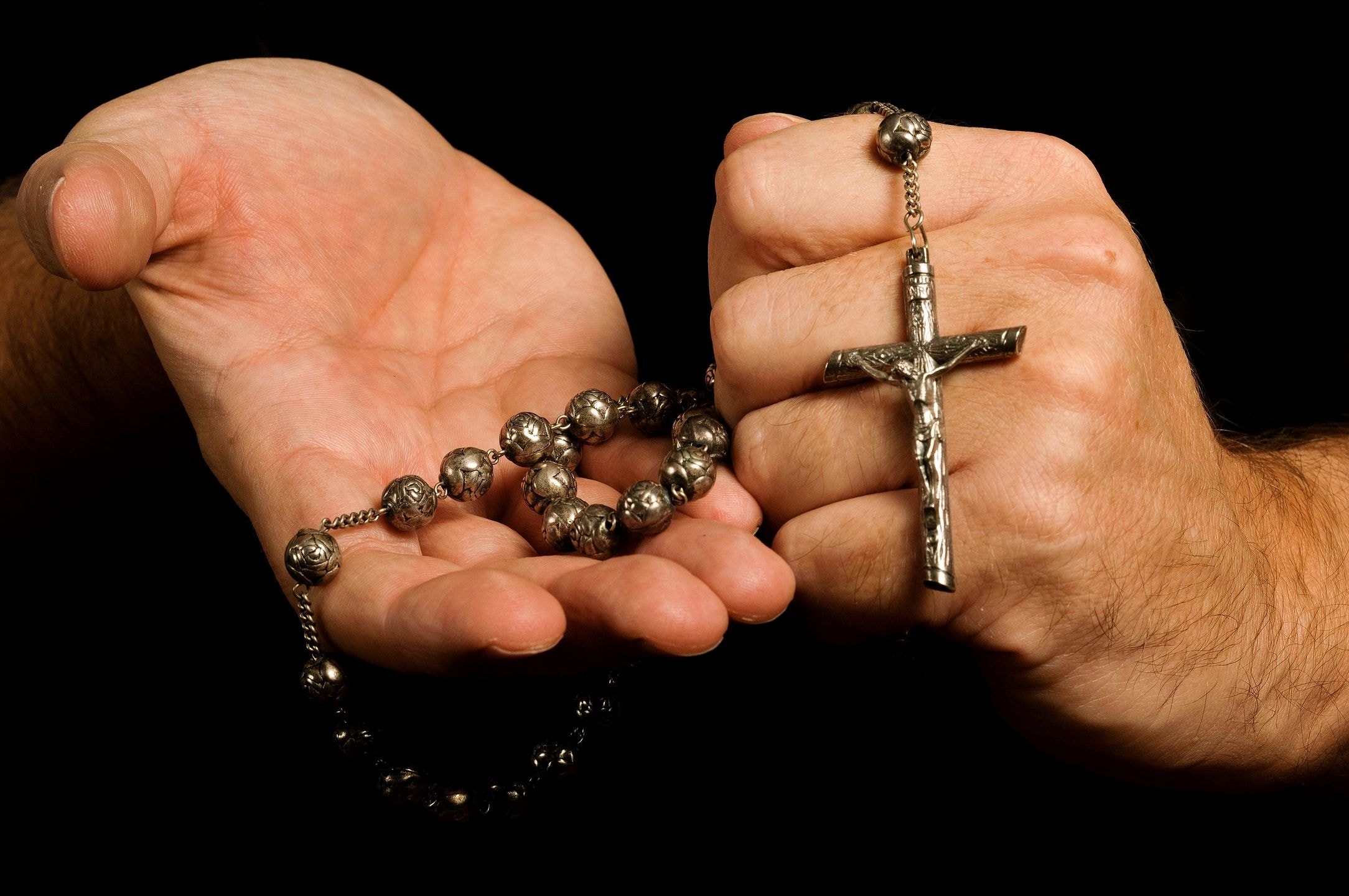 Hands holding rosary beads and cross